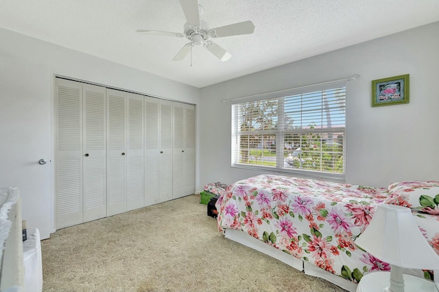 carpeted bedroom featuring ceiling fan, a closet, and a textured ceiling