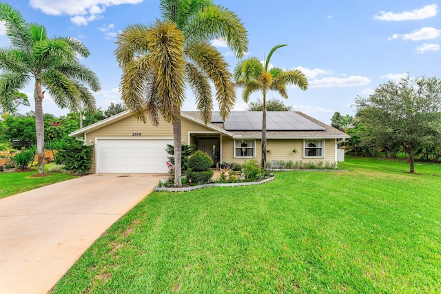 ranch-style house with an attached garage, solar panels, a front yard, and driveway