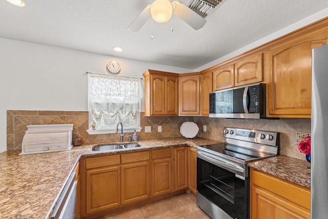 kitchen featuring appliances with stainless steel finishes, backsplash, a sink, and brown cabinets