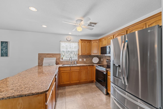 kitchen featuring visible vents, a peninsula, a sink, stainless steel appliances, and backsplash