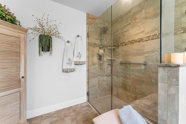 bathroom with a shower stall, baseboards, and tile patterned flooring