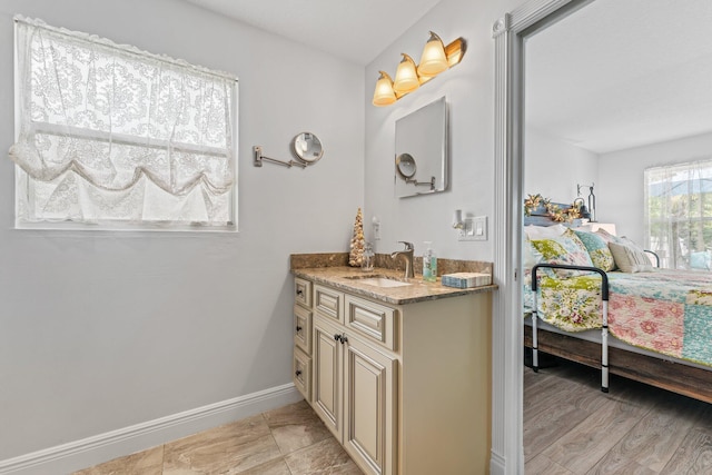 ensuite bathroom with baseboards, connected bathroom, and vanity