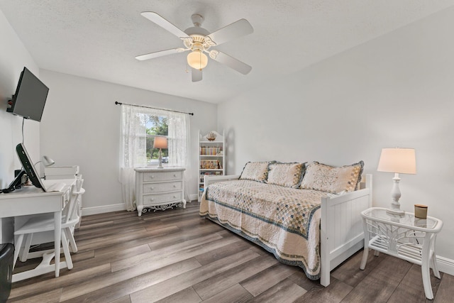 bedroom featuring a ceiling fan, a textured ceiling, baseboards, and wood finished floors