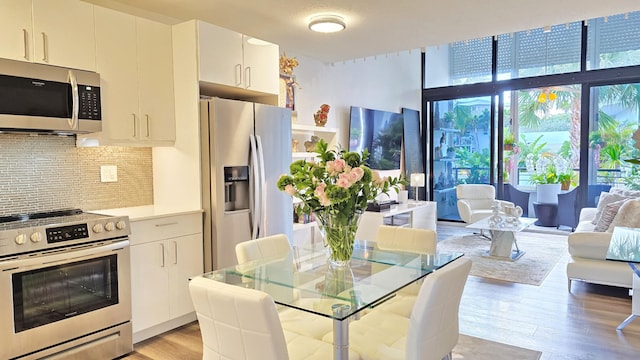 kitchen featuring white cabinetry, decorative backsplash, stainless steel appliances, and light hardwood / wood-style floors