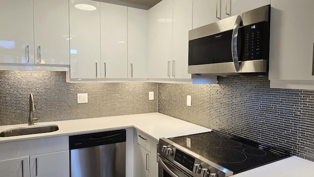 kitchen featuring white cabinetry, sink, backsplash, and appliances with stainless steel finishes