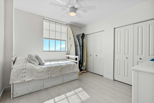 bedroom featuring multiple closets, ceiling fan, and light hardwood / wood-style flooring