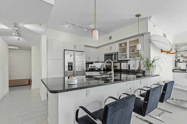 kitchen featuring hanging light fixtures, appliances with stainless steel finishes, a kitchen breakfast bar, and kitchen peninsula