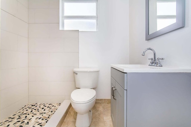 bathroom featuring vanity, toilet, and a tile shower