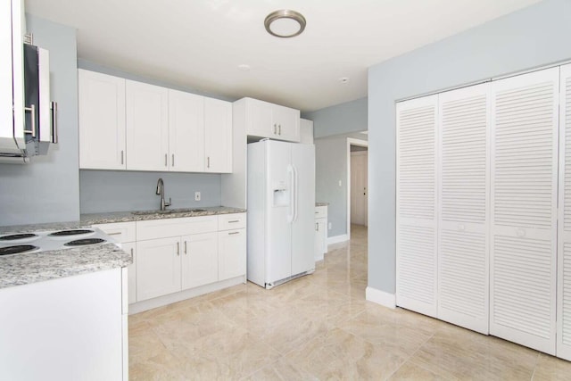 kitchen with sink, white fridge with ice dispenser, and white cabinets