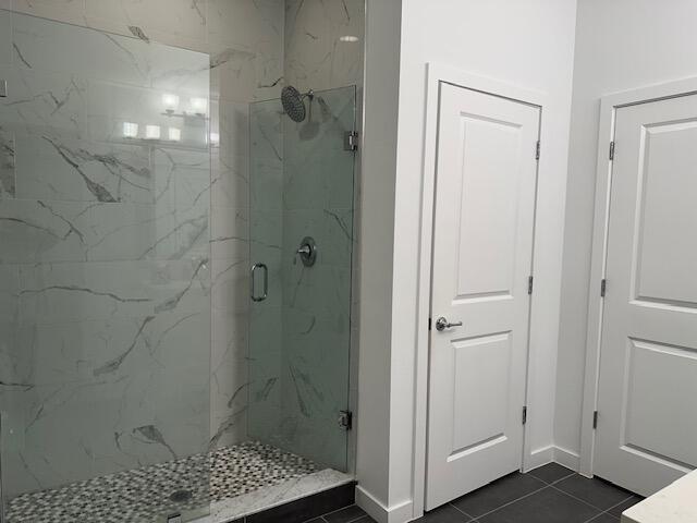 bathroom with an enclosed shower and tile patterned flooring