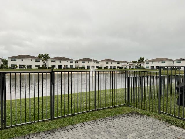 view of gate with a water view and a yard