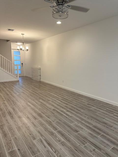 spare room with dark hardwood / wood-style floors and ceiling fan with notable chandelier