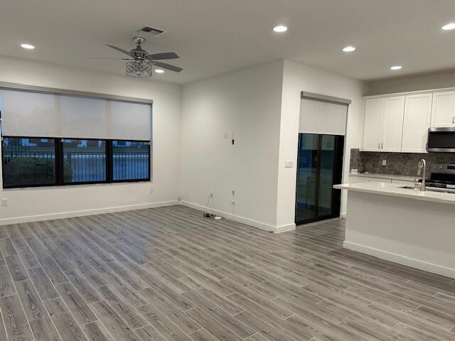 kitchen with white cabinetry, stainless steel appliances, light hardwood / wood-style floors, and backsplash