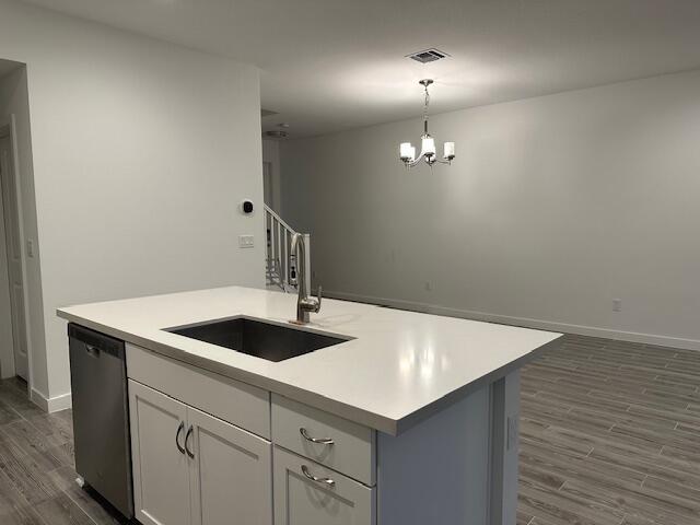 kitchen featuring sink, a center island with sink, dark hardwood / wood-style flooring, dishwasher, and pendant lighting