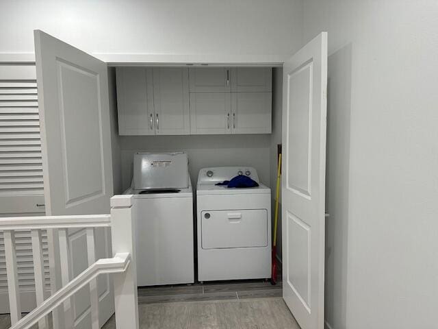 clothes washing area with cabinets and separate washer and dryer