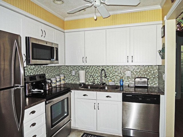 kitchen with sink, white cabinetry, dark stone countertops, ornamental molding, and appliances with stainless steel finishes