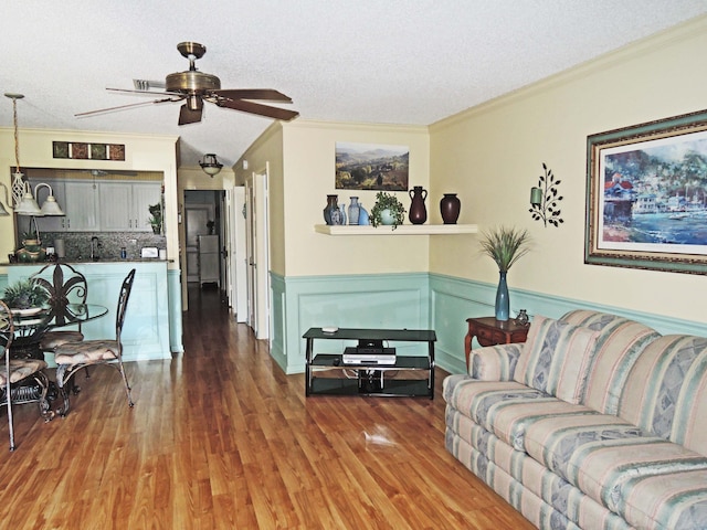 living room featuring ceiling fan, crown molding, wood-type flooring, and a textured ceiling