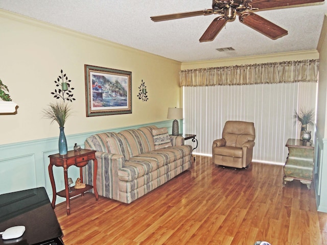 living room featuring crown molding, wood-type flooring, and a textured ceiling