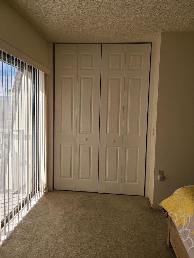 unfurnished bedroom featuring carpet, a textured ceiling, and a closet