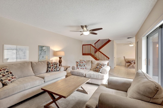 living room featuring light tile patterned floors, a textured ceiling, and ceiling fan