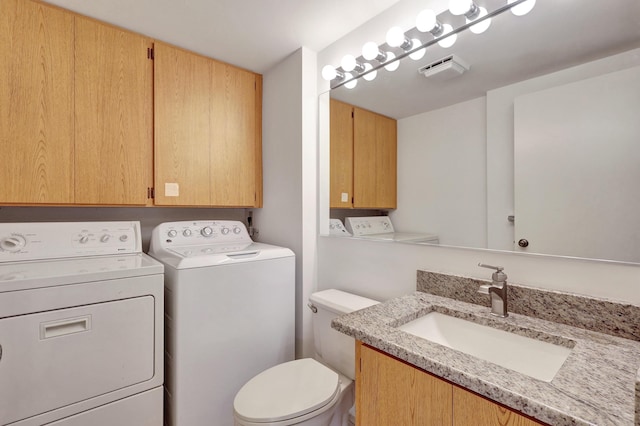 bathroom with washing machine and dryer, vanity, and toilet