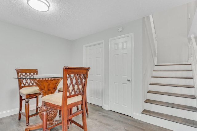 dining space with light hardwood / wood-style flooring and a textured ceiling