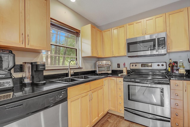 kitchen with appliances with stainless steel finishes, light wood-type flooring, sink, and light brown cabinets