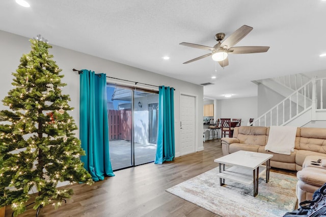 living room featuring a textured ceiling, hardwood / wood-style floors, and ceiling fan