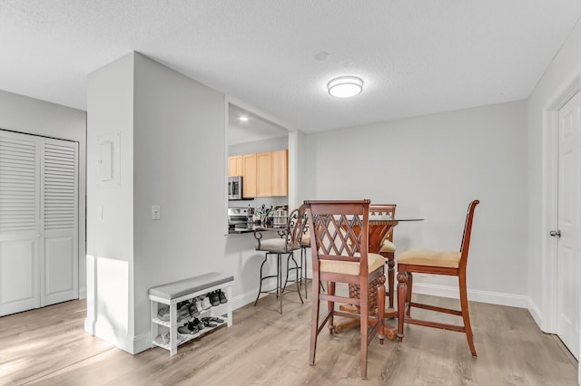 dining space featuring light hardwood / wood-style flooring and a textured ceiling