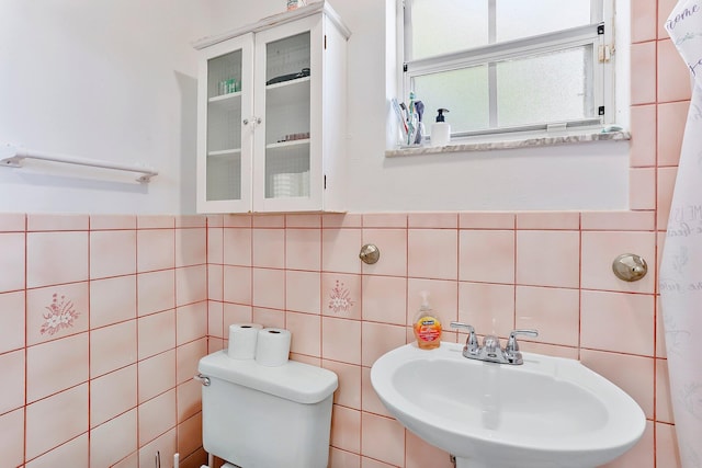 bathroom featuring sink, tile walls, and toilet