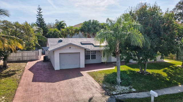 view of front of home featuring a garage, a front lawn, central AC unit, and solar panels