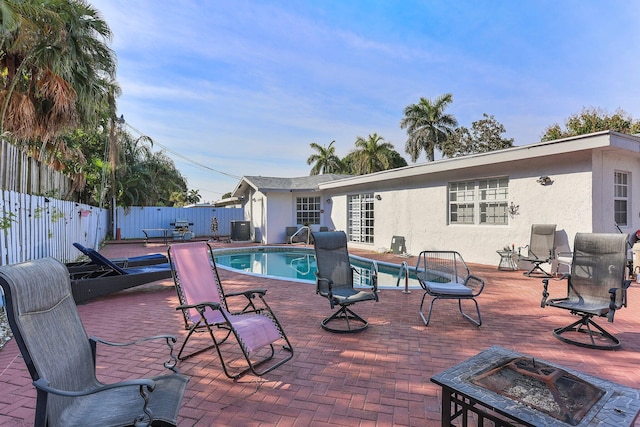 view of swimming pool featuring a patio area, central AC unit, and a fire pit