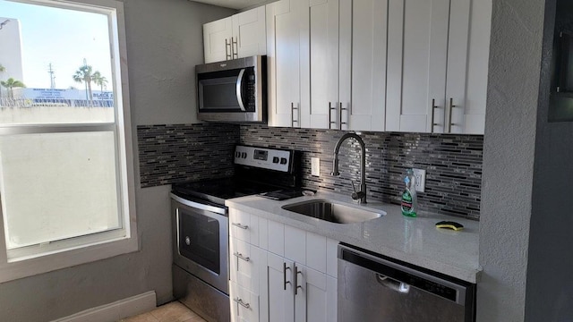 kitchen with white cabinetry, appliances with stainless steel finishes, sink, and backsplash