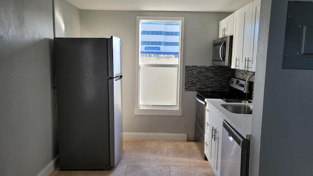 kitchen featuring light tile patterned floors, sink, appliances with stainless steel finishes, white cabinets, and decorative backsplash