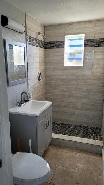 bathroom with vanity, toilet, and a tile shower