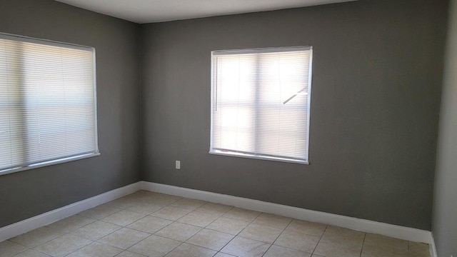 spare room with light tile patterned floors and a wealth of natural light