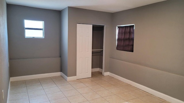 unfurnished bedroom with light tile patterned floors and a closet