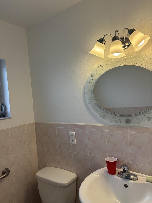 bathroom featuring toilet, sink, and tile walls