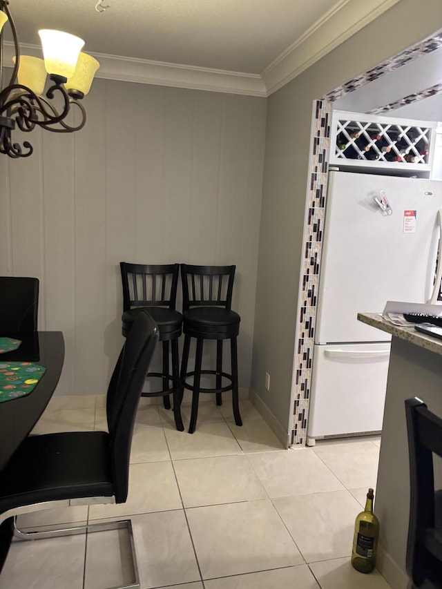 dining area featuring crown molding, a chandelier, and light tile patterned flooring