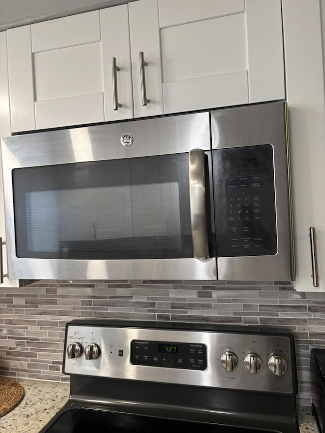 details featuring stainless steel appliances, white cabinetry, tasteful backsplash, and light stone counters