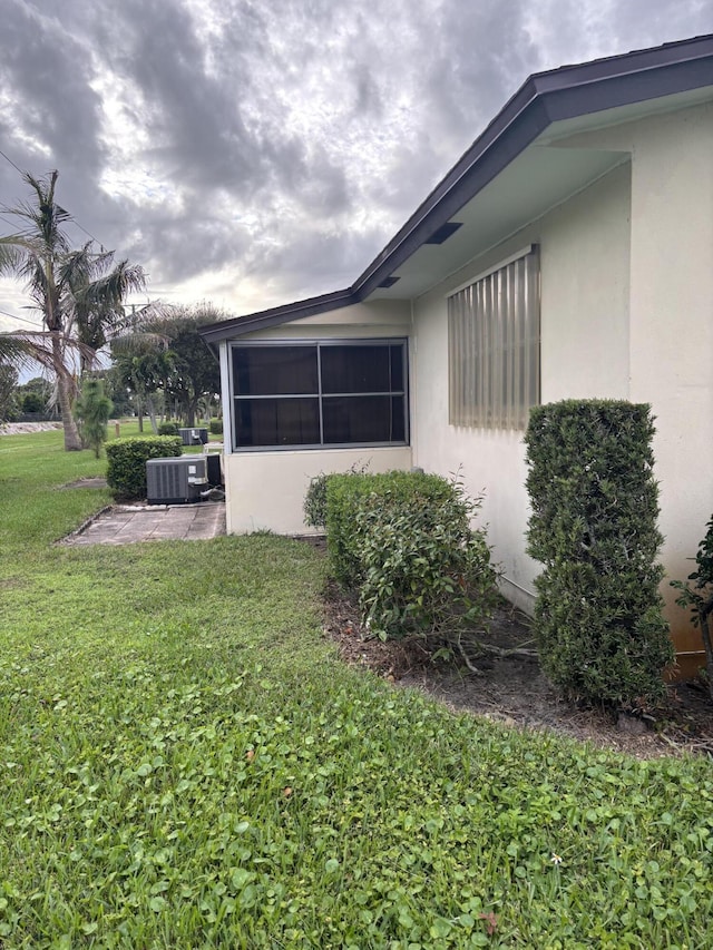 view of side of property with a yard, a patio area, and central AC