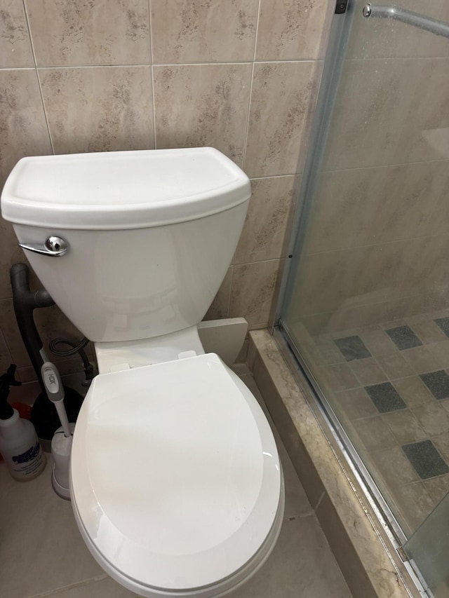 bathroom featuring tile walls, tile patterned floors, and a shower with shower door