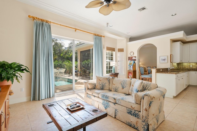 living room featuring crown molding, sink, light tile patterned floors, and ceiling fan