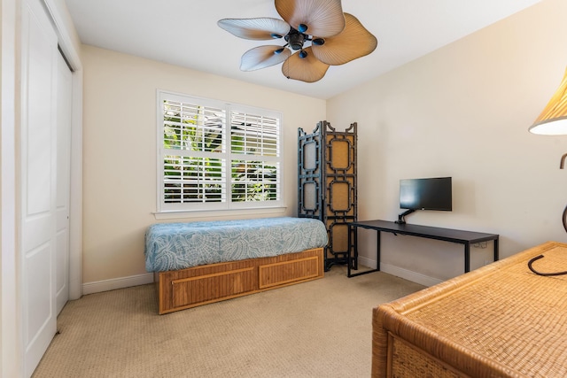 bedroom featuring ceiling fan, light carpet, and a closet