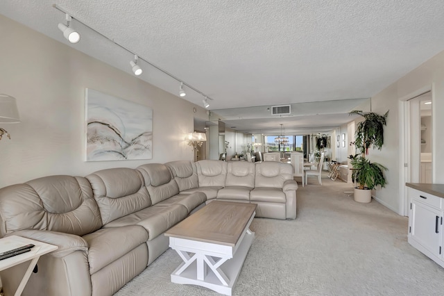 carpeted living room with a notable chandelier and a textured ceiling