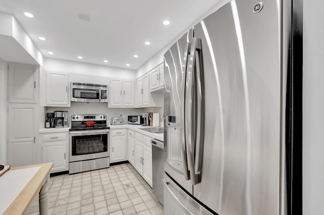 kitchen featuring white cabinetry, appliances with stainless steel finishes, sink, and light tile patterned floors