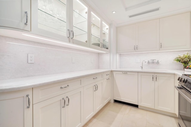 interior space with tasteful backsplash, stove, sink, and white cabinets