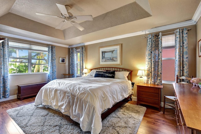 bedroom with crown molding, hardwood / wood-style flooring, baseboard heating, a tray ceiling, and a textured ceiling