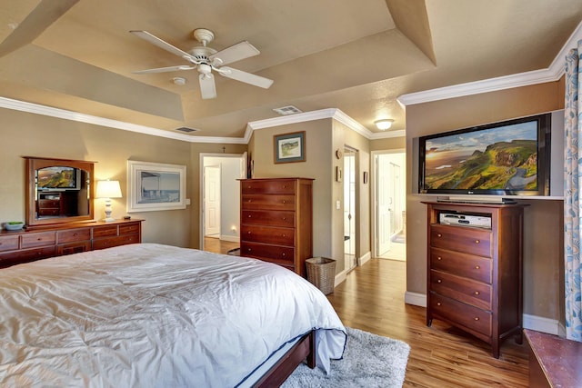 bedroom featuring ornamental molding, ceiling fan, light hardwood / wood-style floors, and a tray ceiling