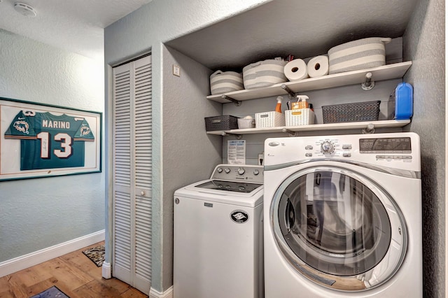 laundry room featuring washing machine and clothes dryer and light hardwood / wood-style floors